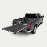 Gray pickup truck with an extended DECKED CargoGlide sliding bed tray on a light neutral background