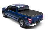 Rear three-quarter view of a blue Ford F-150 with a closed TruXedo TruXport soft roll-up tonneau cover