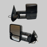 Pair of black power heated telescoping towing mirrors for GMC and Chevrolet trucks on a light neutral background