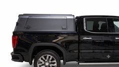 Side view of a black GMC Sierra with an IRONHAUL aluminum truck canopy and side-access panel.