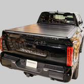 Black Ironhaul hard folding flush mount tonneau cover installed on a black Toyota Tundra with a light neutral background