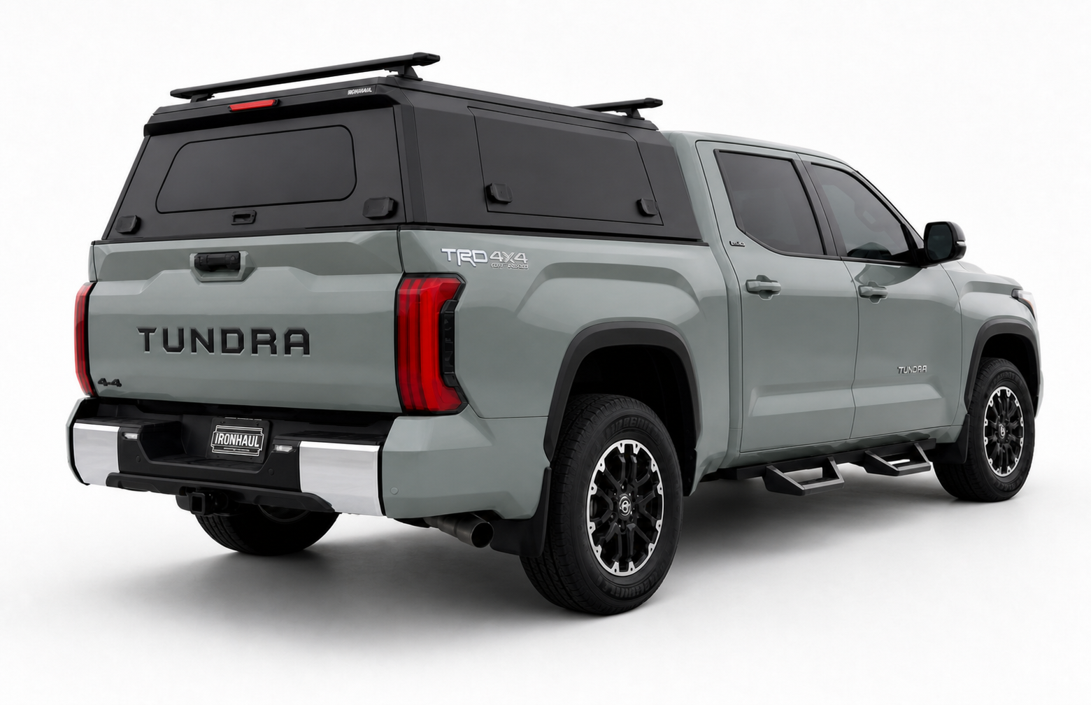 Rear right-side view of a grey Toyota Tundra with an IRONHAUL aluminum truck canopy V2, side access door, rear window, and roof cross bars