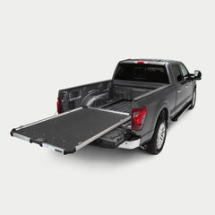 Gray pickup truck with an extended DECKED CargoGlide sliding bed tray on a light neutral background
