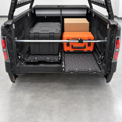 IRONHAUL adjustable cargo bar securing boxes and tool cases across a pickup truck bed