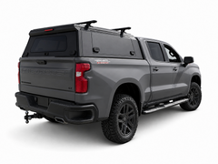 Grey Chevrolet Silverado with a black IRONHAUL aluminum truck canopy and roof crossbars, shown from the rear-right angle