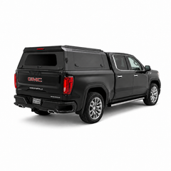 Rear three-quarter view of a black GMC Sierra Denali with an IRONHAUL aluminum truck canopy, side access door, and rear window