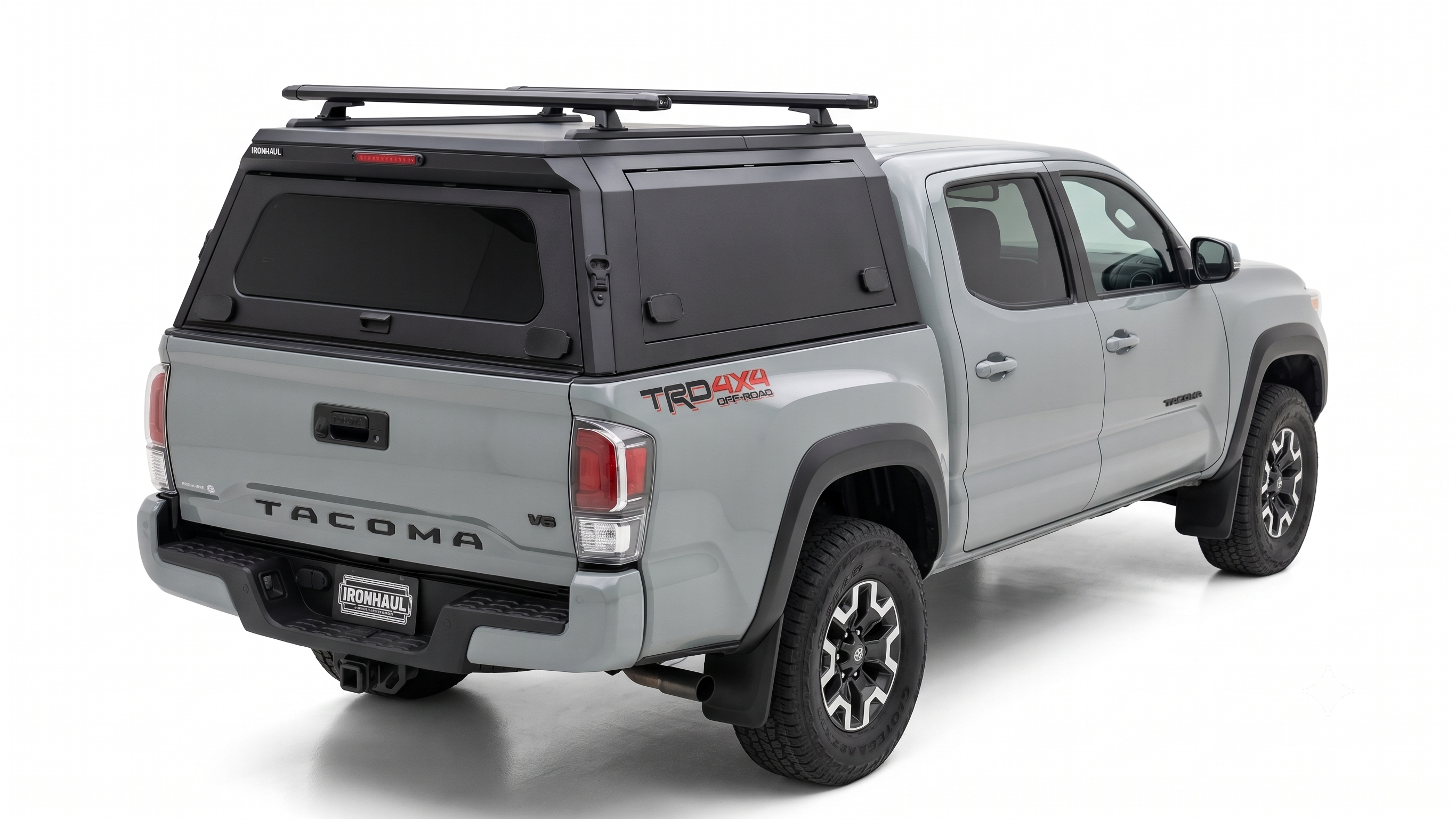 Silver Toyota Tacoma with an IRONHAUL aluminum truck canopy V2, side access doors, and roof racks
