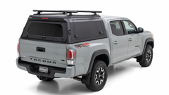 Silver Toyota Tacoma with an IRONHAUL aluminum truck canopy V2, side access doors, and roof racks